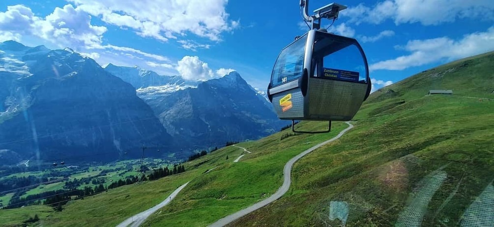 A cable car ascending a mountain with a clear sky and a valley below. 5