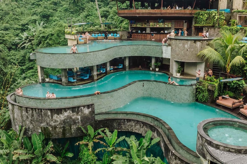 A multi-level swimming pool complex surrounded by lush greenery. 3