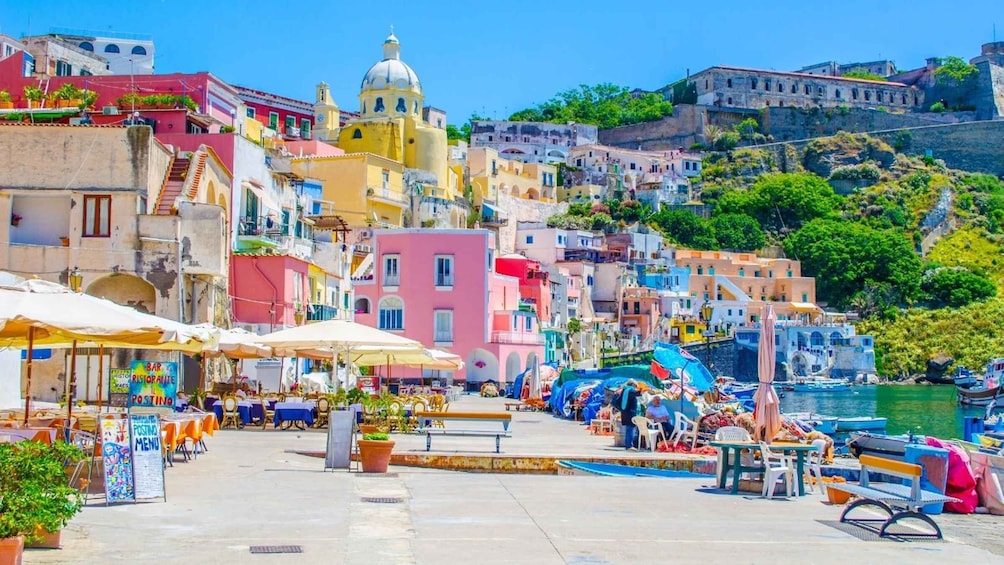 A colorful coastal town with a prominent church, a bustling waterfront with boats, and a hillside with historic buildings. 3