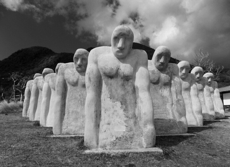 A row of large stone statues with a mountainous backdrop. 2