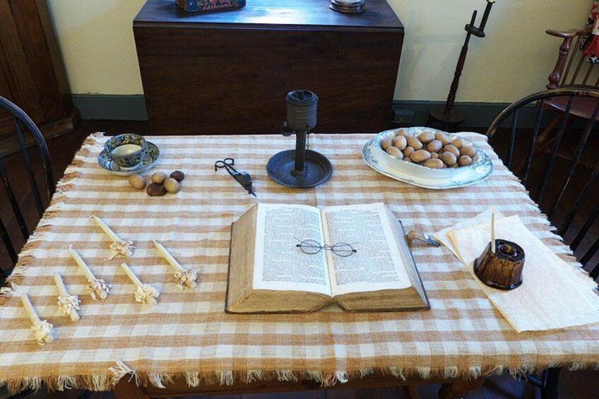 Une table avec un livre ouvert, un bol d’œufs, une bougie et une paire de ciseaux. 2