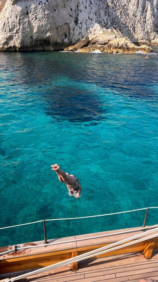 A person diving into clear blue water from a wooden dock. 4