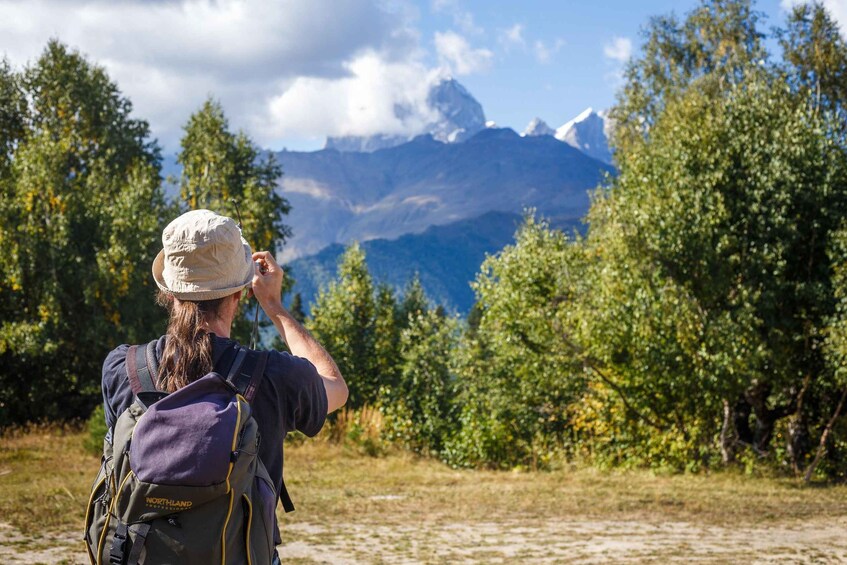 A person hiking with a Northland backpack, surrounded by trees and mountains. 3