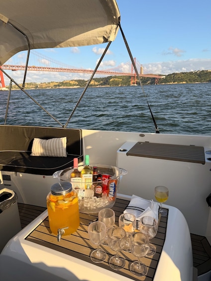 A boat with a table set for drinks, a bottle of champagne, and a view of a bridge over water. 3