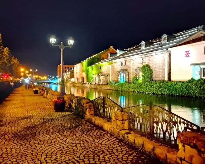 A cobblestone street at night with illuminated buildings and a canal. 2