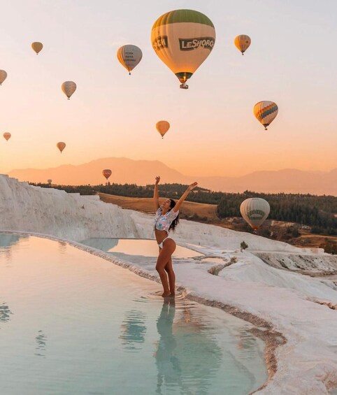 A person standing by a pool with hot air balloons in the background. 4