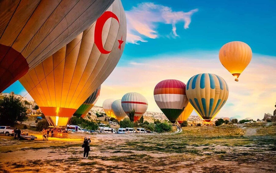 A hot air balloon festival with multiple balloons in various colors and patterns, set against a backdrop of a clear sky and a mountainous landscape. 2