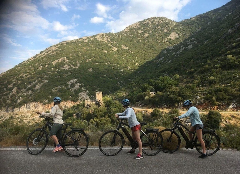 Three cyclists on a road with a mountainous backdrop. 3