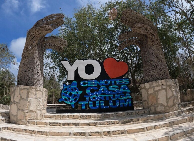 A sign with 'YO' and a heart, surrounded by stone steps and trees. 1