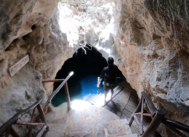 A cave entrance with wooden railings and a sign. 4