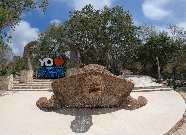 A sculpture of a reclining figure in a park with a sign reading 'YO LOVE YOUR HOME' and a stone staircase. 5