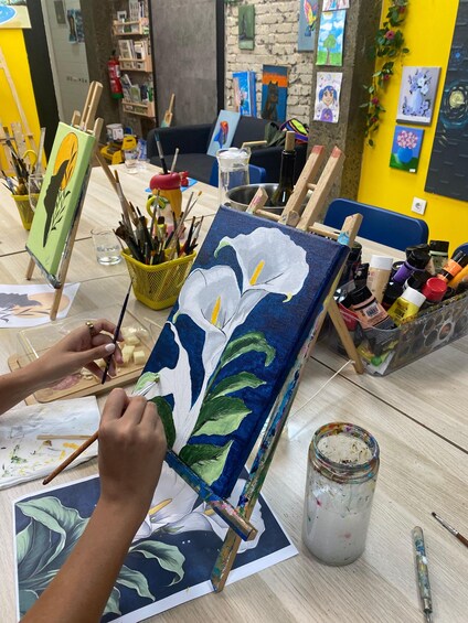 An artist painting a floral design on a canvas. 1
