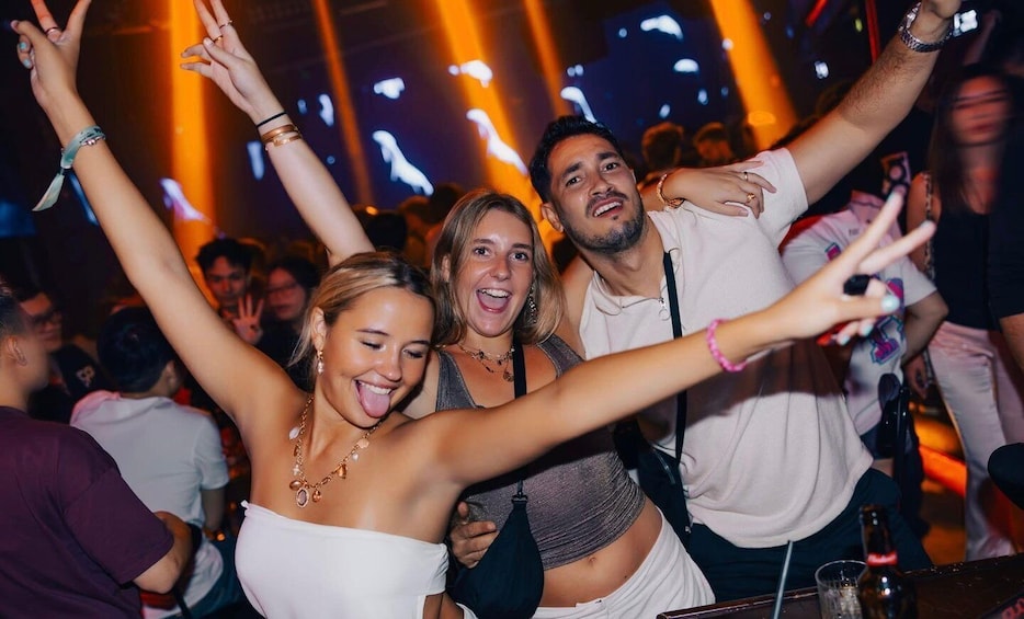 A crowded indoor event with people raising their hands and taking photos. 4