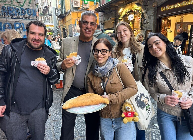 A group of people enjoying street food in a bustling urban area with historic buildings and graffiti. 1