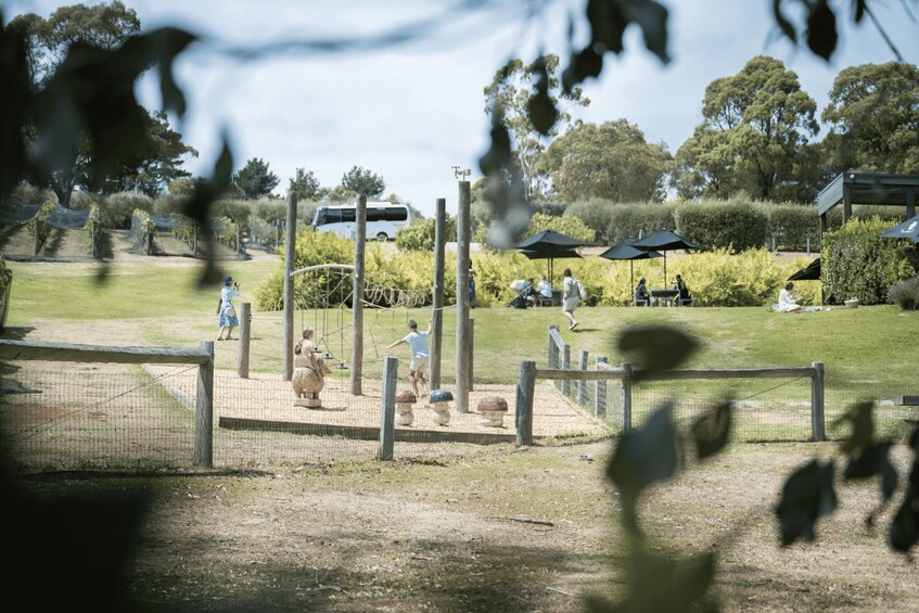 A park with a fenced area, people playing, and a white van in the background. 5