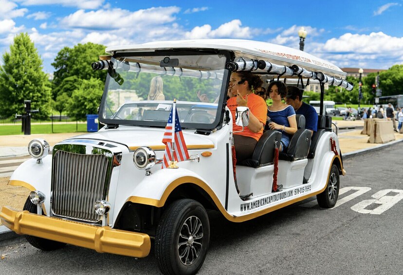 A vintage car with a flag on the front, passengers inside, and a website URL on the side. 2