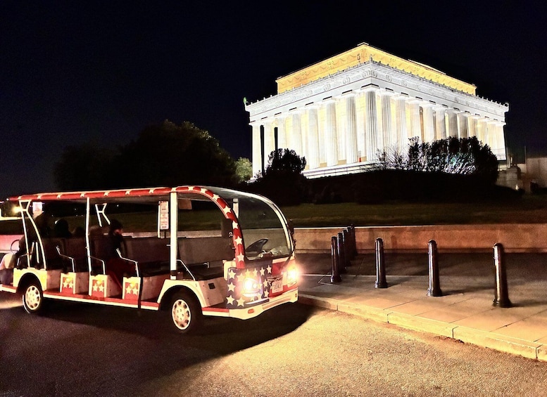 A brightly lit tour bus with star decorations parked in front of the Lincoln Memorial. 1