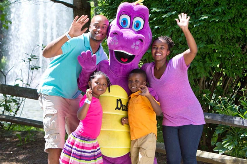 A group of people posing with a purple mascot and a yellow barrel. 5