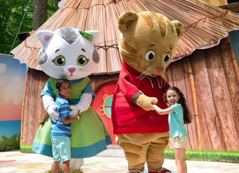 A person in a large cat costume and a person in a red outfit standing in front of a colorful backdrop with a large umbrella. 1