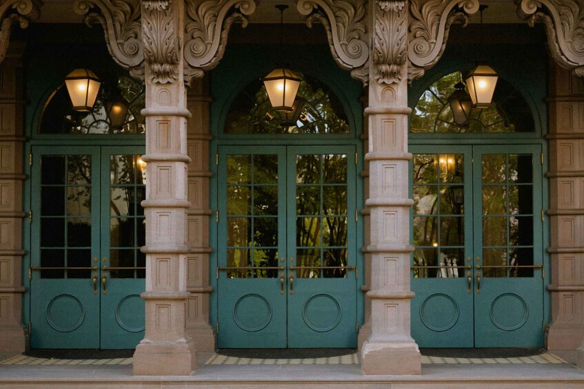 A building facade with green doors, ornate columns, and decorative lighting. 2