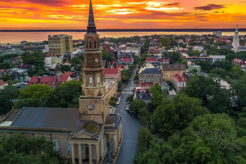 A cityscape at sunset with a prominent church tower and a waterfront in the background. 5