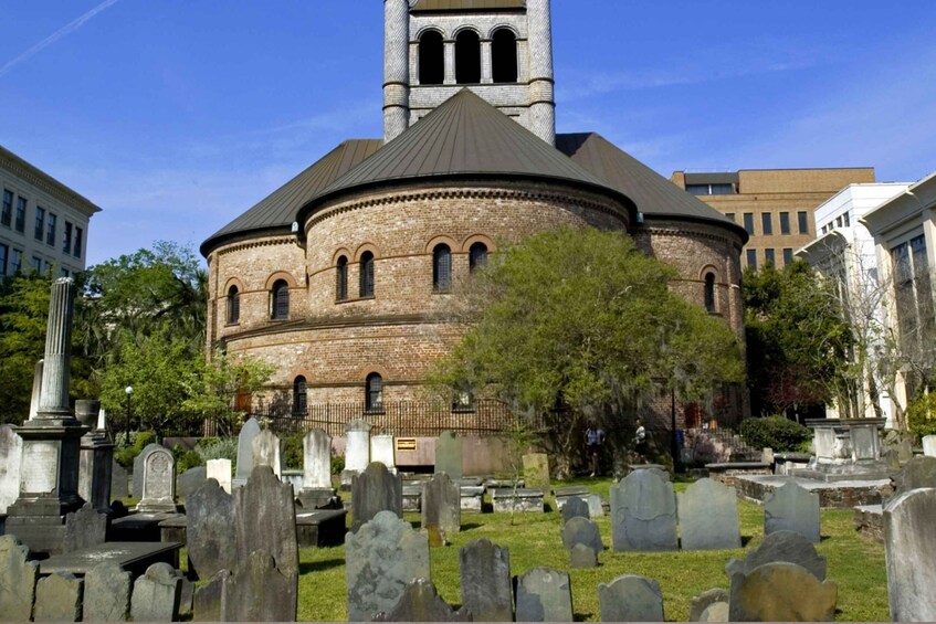 A church with a brick facade and a tower, surrounded by a cemetery with headstones. 1