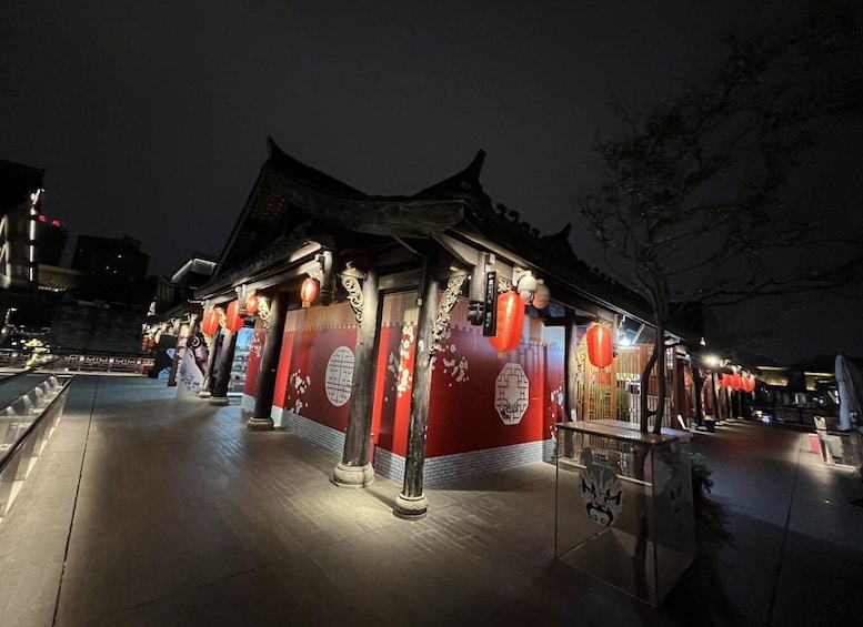 A traditional building with red walls and Chinese characters, illuminated by lanterns at night. 5