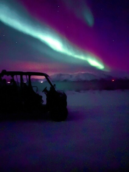 A vehicle on snow-covered terrain with aurora borealis in the sky. 5