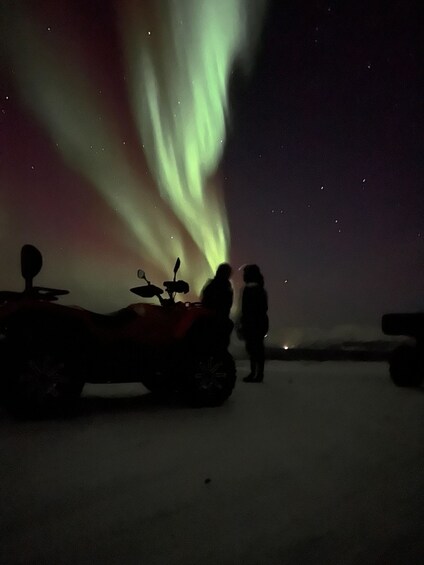 A snowy landscape with a person and an ATV under the aurora borealis. 3