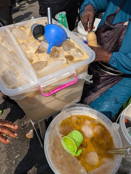 A person preparing a drink with ice and a lime in a plastic container. 3