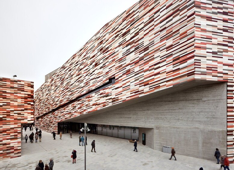 A modern building with a patterned facade and a covered walkway. 1