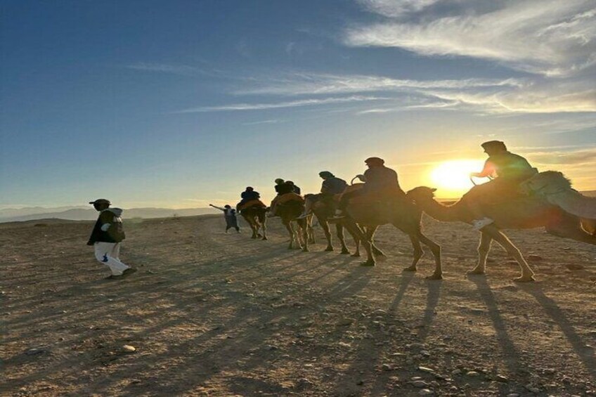 Un grupo de personas montando camellos en un paisaje desértico durante el atardecer. 1