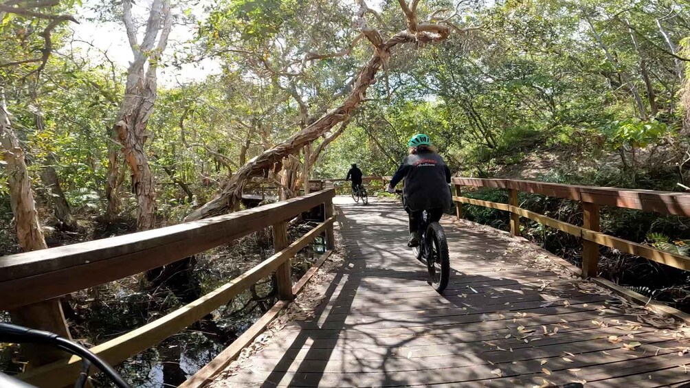 A wooden bridge in a forest with cyclists. 5