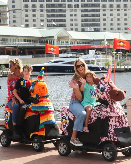 A person riding a colorful, animal-shaped vehicle with a child and an adult. 2