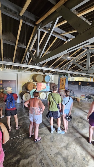 A group of people inside a building with a high ceiling and exposed beams, standing in front of barrels and informational displays. 4