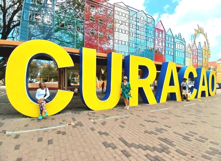 Large yellow letters spelling 'CURACAO' with a person sitting inside one of the letters. 1