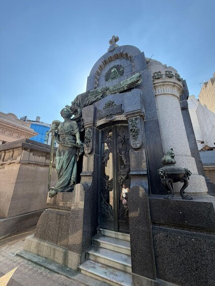 A stone monument with a statue of a woman and a lion, a staircase leading up to it, and a plaque reading 'Cristo Redentor.' 3