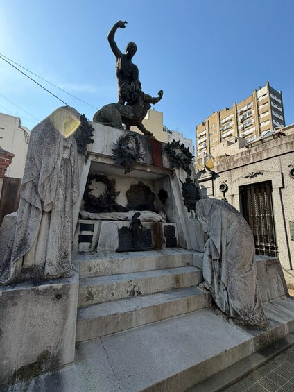 A stone monument with a central statue, surrounded by steps and decorative elements. 2
