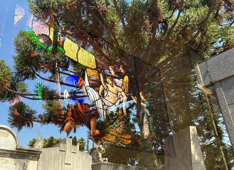A stained glass window with figures, surrounded by trees. 4