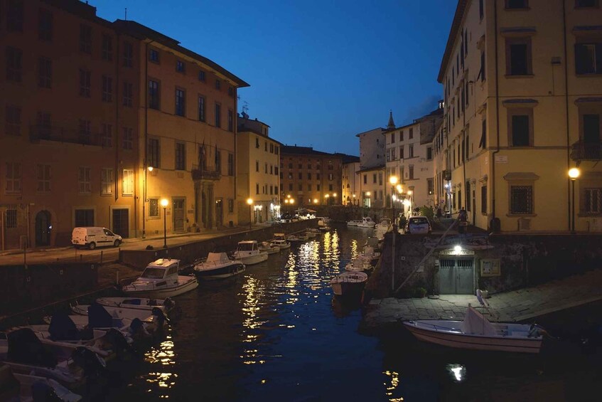 A canal lined with boats and buildings at dusk. 3