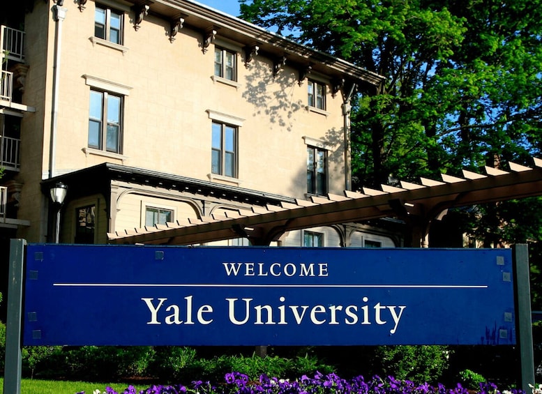A sign reading 'Welcome Yale University' with a building in the background. 1