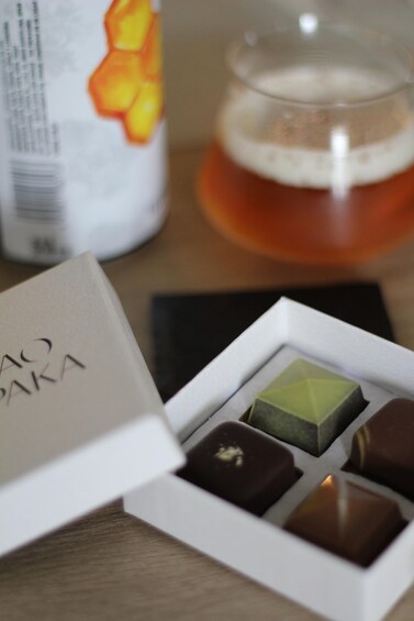 A box of assorted chocolates and a glass of beer on a table. 1