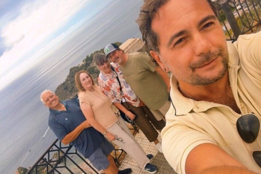A group of people standing by a waterfront with a railing and a body of water in the background. 2