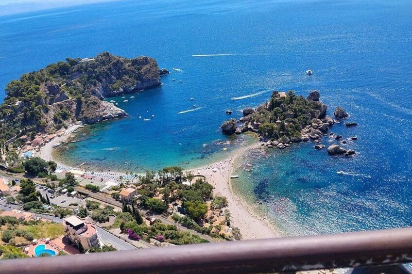 A coastal landscape with a beach, rocky outcrops, and clear blue waters. 4