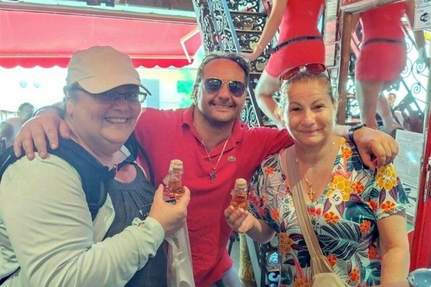 Three people holding bottles, a red awning, and a mannequin in the background. 3