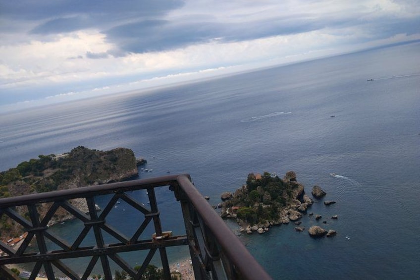 A coastal landscape with a rocky island and a metal railing. 4