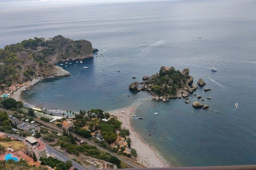 A coastal town with a beach, boats, and a rocky island. 3