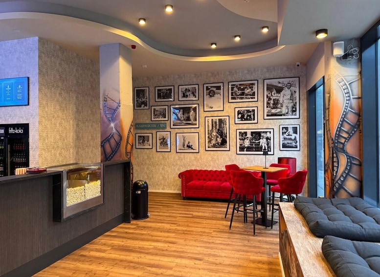A modern interior with a wooden floor, red and black seating, and a wall adorned with black-and-white photographs. 5