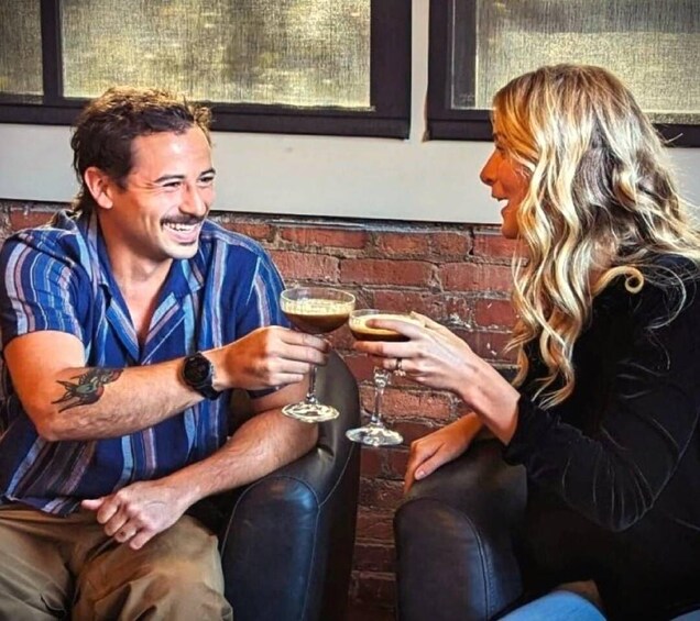Two people sitting on a bench, holding drinks. 5