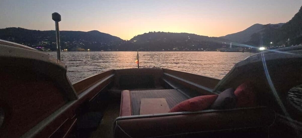 A boat on a calm river at dusk with mountains in the background. 3